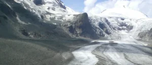 sloshy snowmobile trail with rocky partially-snow-covered maintains in the background