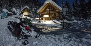 snowmobile parked outside a winter cabin on a starry night