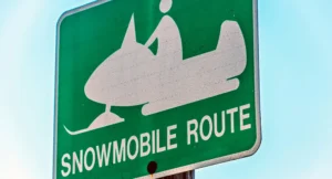 A green road sign depicting a snowmobile with the words snowmobile route underneath
