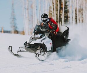 man on a snowmobile travels at high speeds across a snowy field