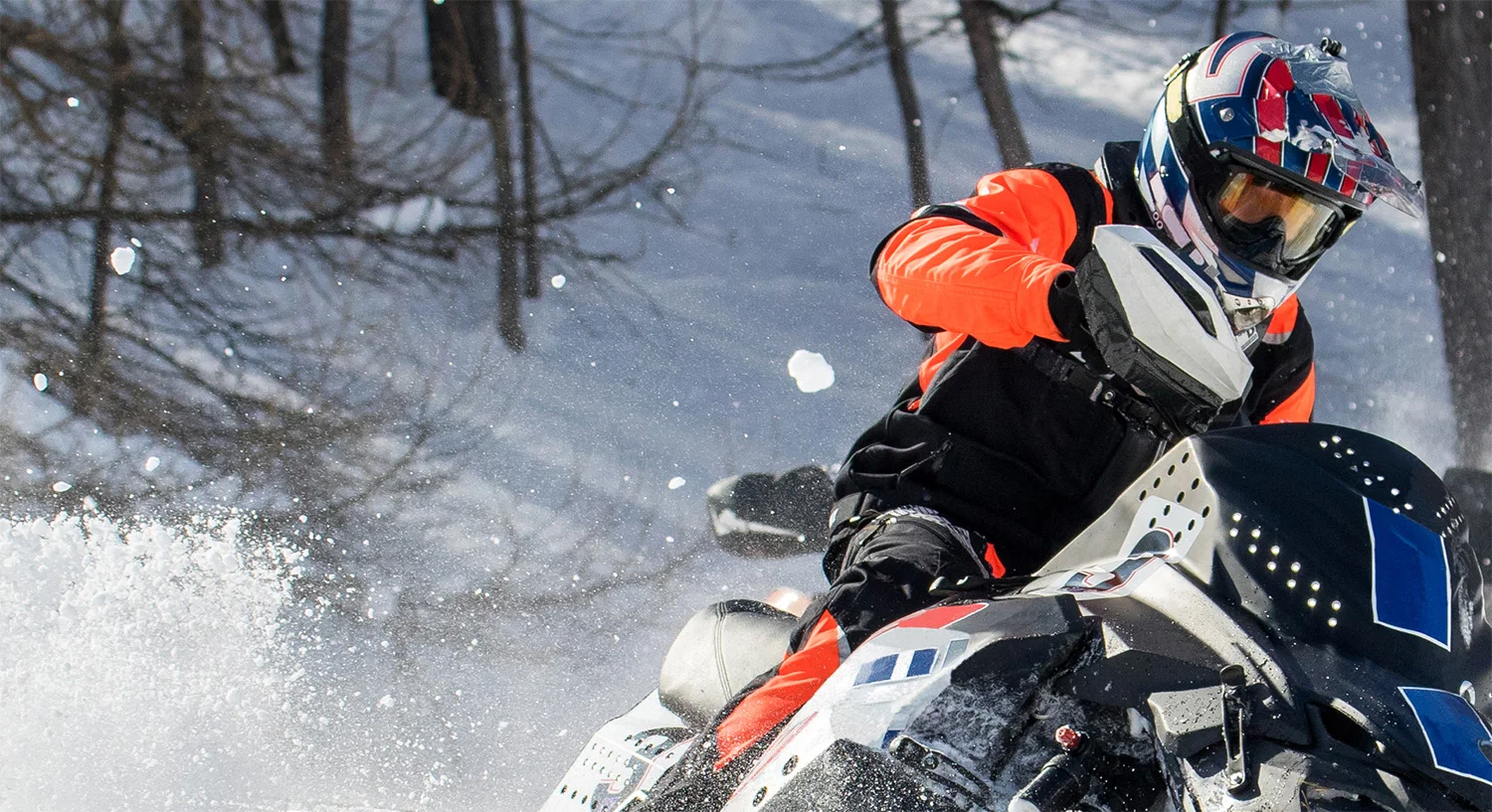 a snowmobiler traveling past on a snowy trail