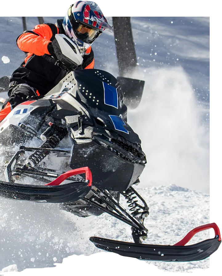 a snowmobile plows through fresh now in a forest